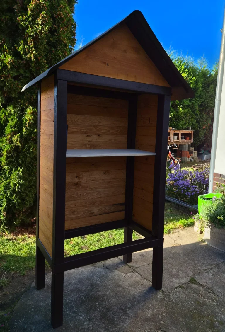 Offene Vorderseite des Bücherhauses mit verkleideten Seiten, hölzerner Rückwand und einem ersten, noch ungestrichenen Einlegeboden.